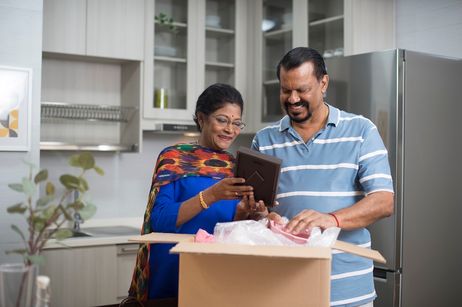 elderly couple unpacking a box and looking at a photo frame