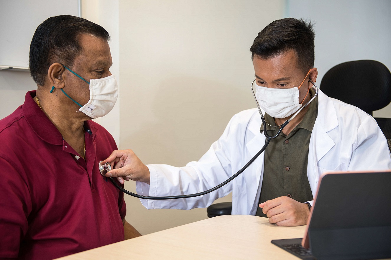 Young Asian doctor talking to elderly patient