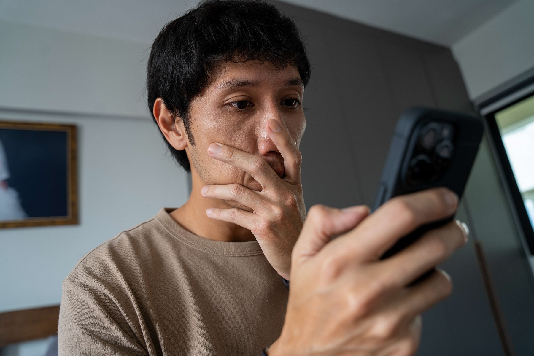 man looking shocked while looking at his phone