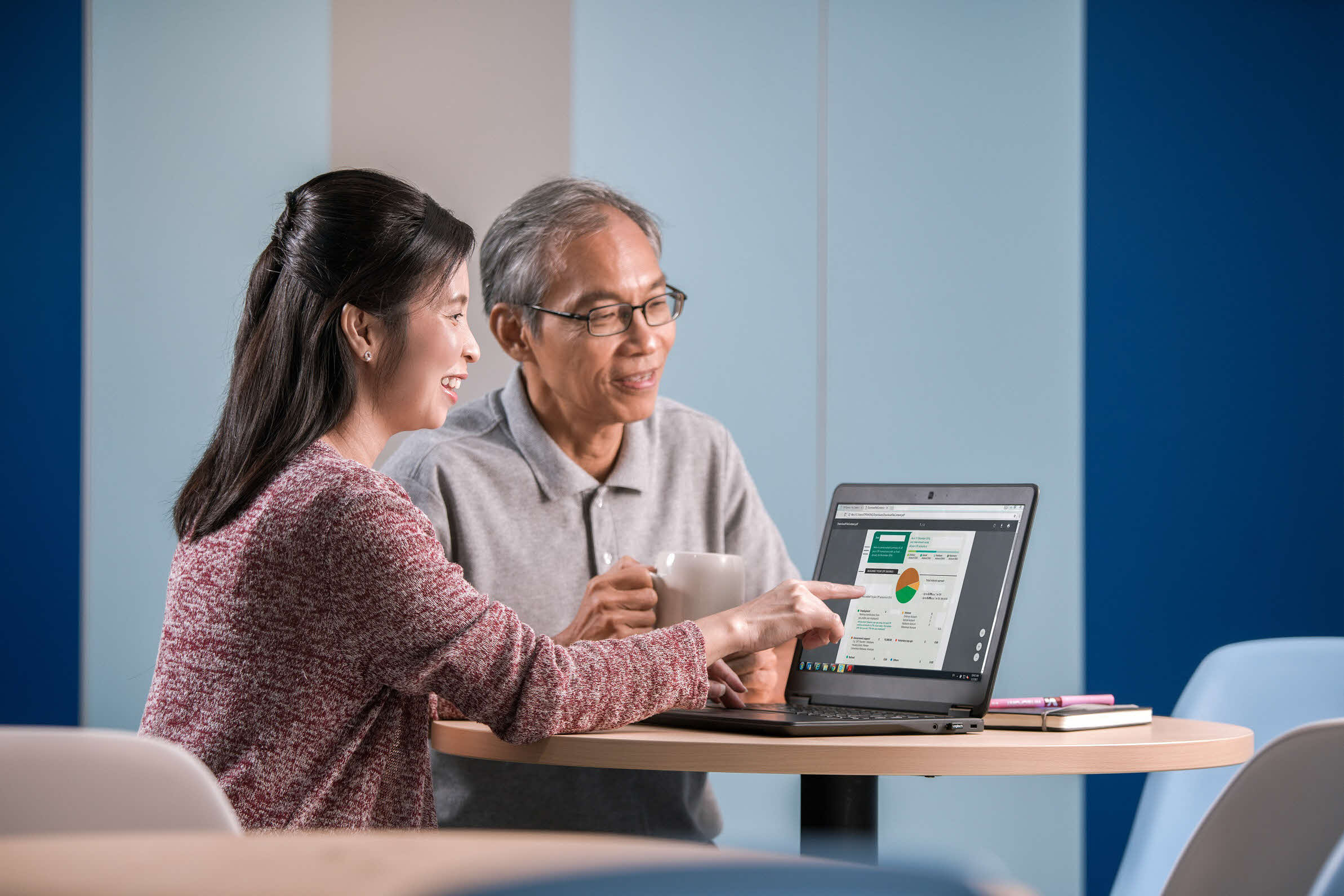 a young woman guiding an elderly man to use the laptop 