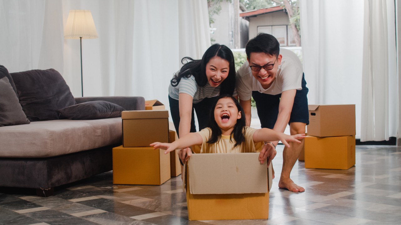 Happy young Asian family moving into their new home, having fun with their daughter
