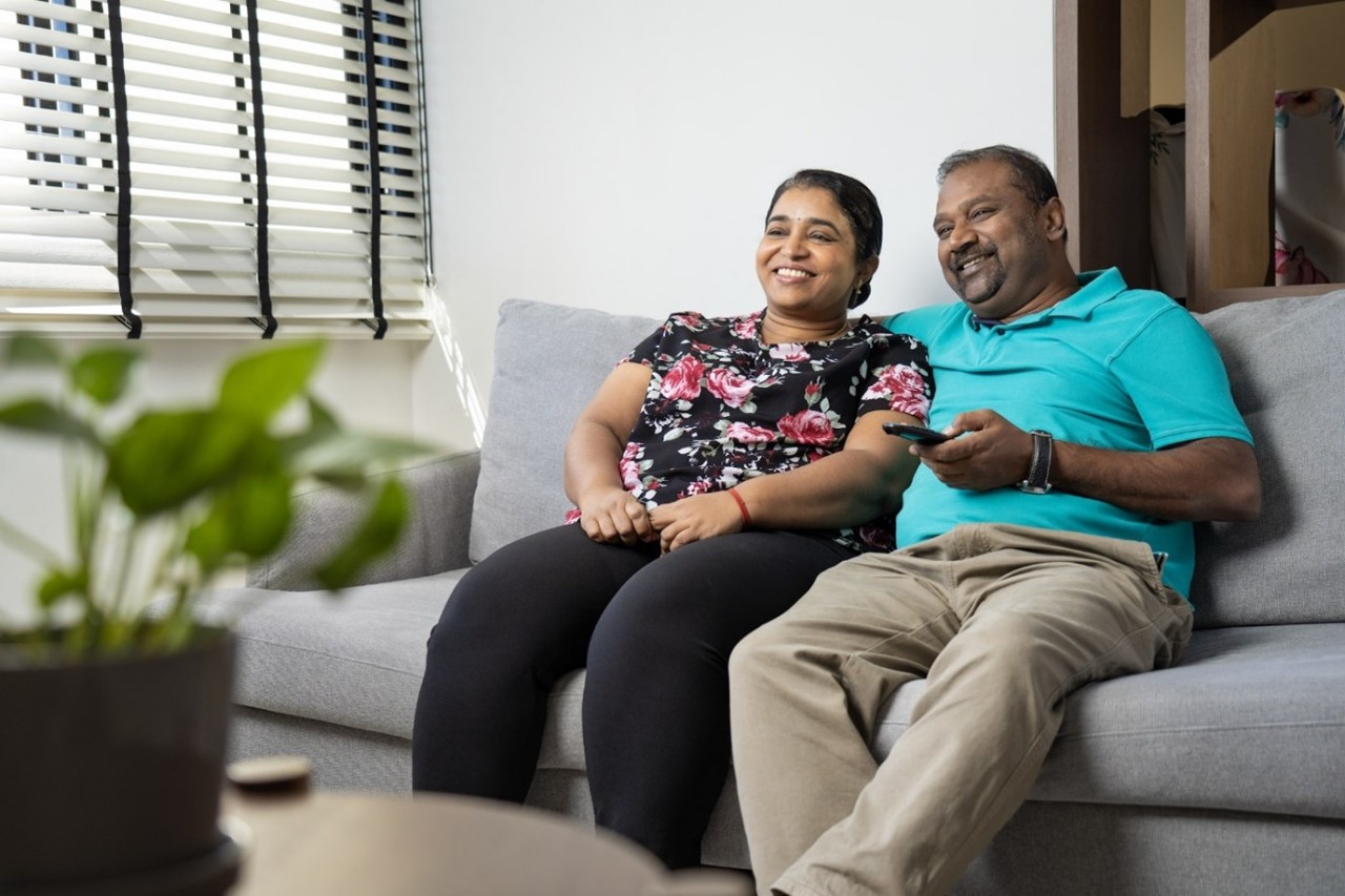 Couple seated together at home watching tv