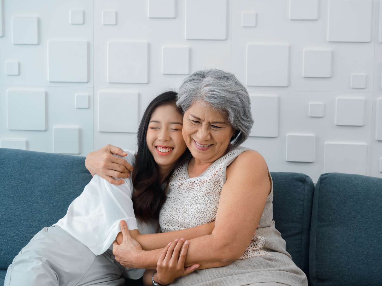 Elderly woman tenderly hugging younger woman