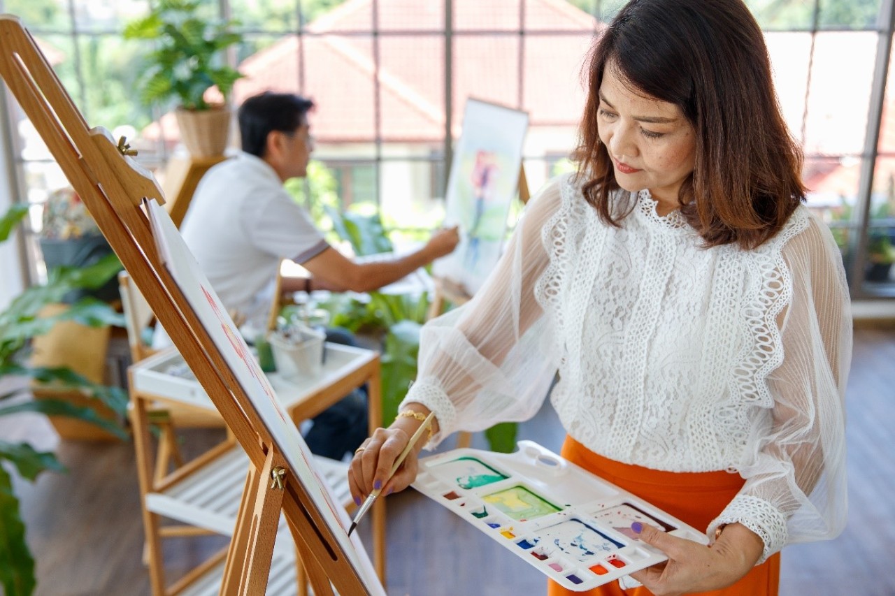 Asian lady holding a palette and painting a canvas
